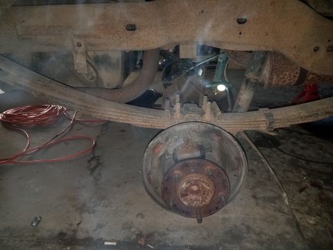 1996 Ford Bronco - Close-up view of the rear axle and suspension components, including a drum brake assembly and leaf springs.