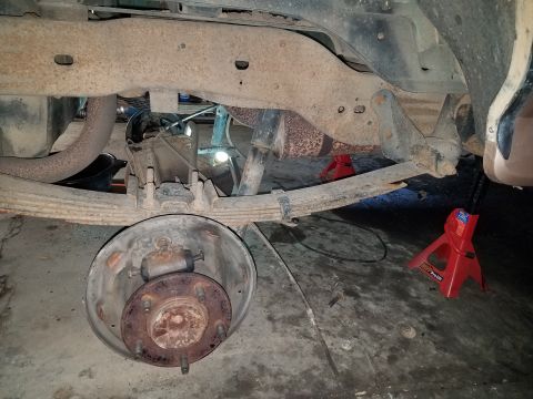1996 Ford Bronco - Undercarriage view of a vehicle's rear suspension and axle components during maintenance.