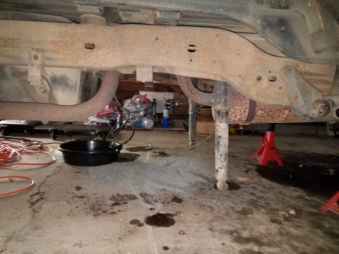 1996 Ford Bronco - The underside of a vehicle is shown, with focus on the frame, exhaust system, and suspension components, during what appears to be maintena…