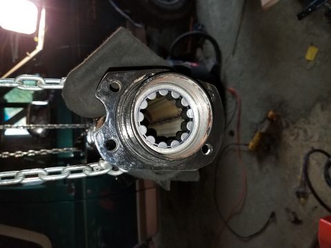 1996 Ford Bronco - A close-up view of a vehicle's axle hub, showing its splined interior, secured by a chain.