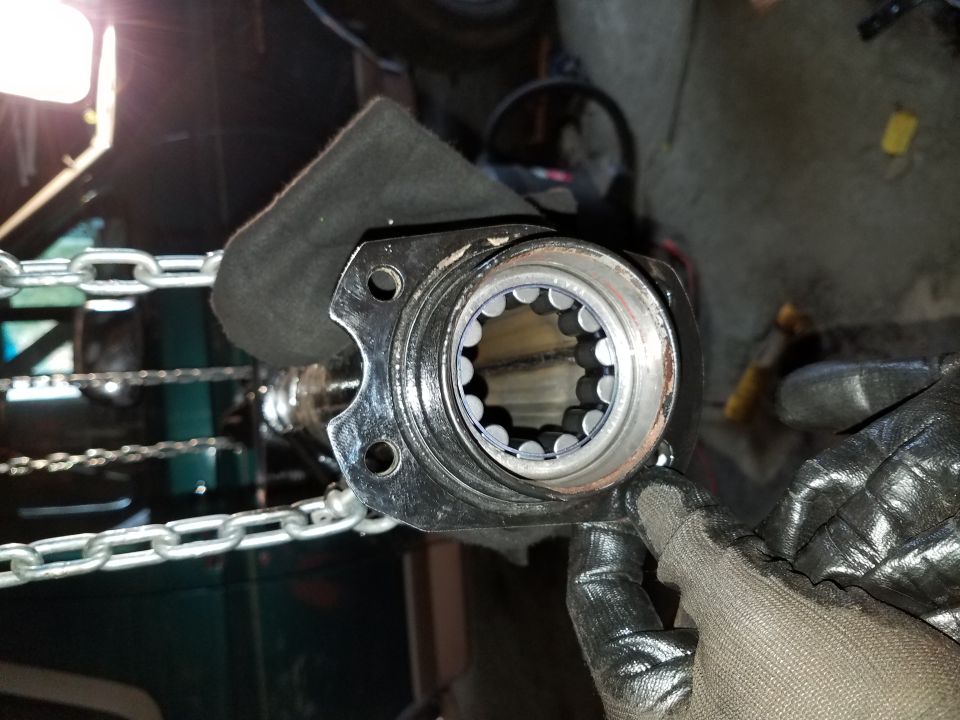 Splined shaft hub with roller bearings, held by gloved hands, with chains in background