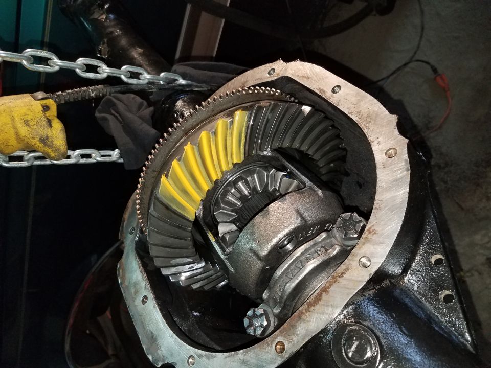 Open differential housing with ring gear and spider gears, yellow marking compound visible.