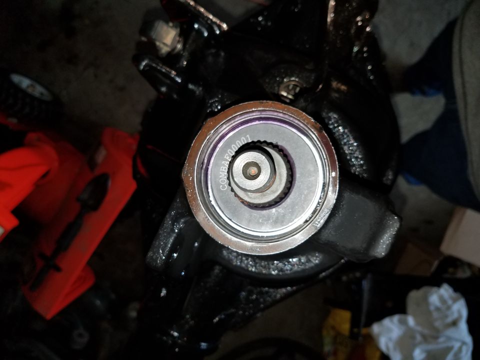 Overhead view of a black steering gear box with a silver cap and purple lettering.