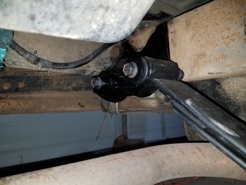 1996 Ford Bronco - A black aftermarket suspension component, likely a shackle or bracket, is bolted to the frame of a vehicle, connecting to a leaf spring. Th…