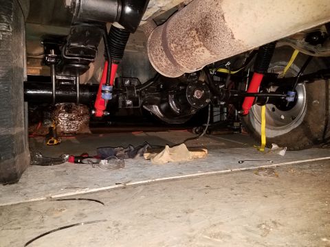 1996 Ford Bronco - The underside of a vehicle, likely a 1996 Ford Bronco, showing the rear axle, suspension components including red shock absorbers, and part…