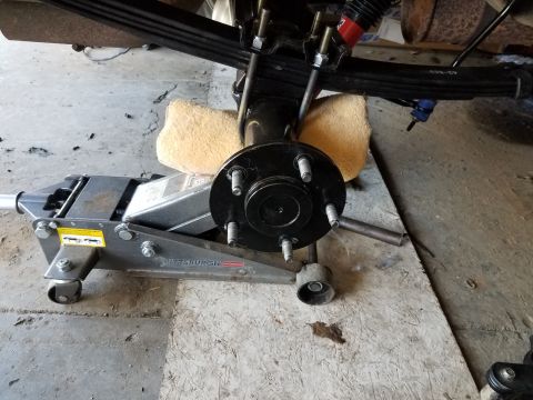 1996 Ford Bronco - A hydraulic floor jack is supporting the rear axle assembly of a vehicle, which is suspended by leaf springs. A wheel hub with five studs i…