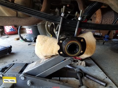 1996 Ford Bronco - A close-up, low-angle shot shows the underside of a vehicle's rear axle assembly, supported by a hydraulic jack and cushioned with towels.…