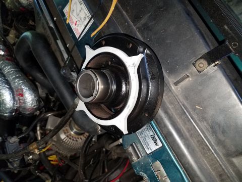 1996 Ford Bronco - A close-up view of a black and silver automotive part, possibly a pulley or hub assembly, is mounted in an engine bay. The part has a silve…
