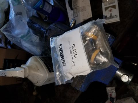 1996 Ford Bronco - A clear plastic bag containing a U-joint part labeled "Bronco Graveyard" and "1330 Tom Woods U-Joint GS133" is placed on a blue vise. A pac…