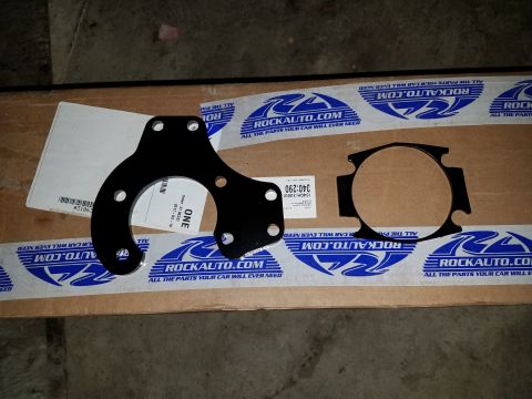 1996 Ford Bronco - Two black metal brake caliper brackets are laid out on a cardboard box with RockAuto.com branding. The box has tape with the RockAuto.com l…