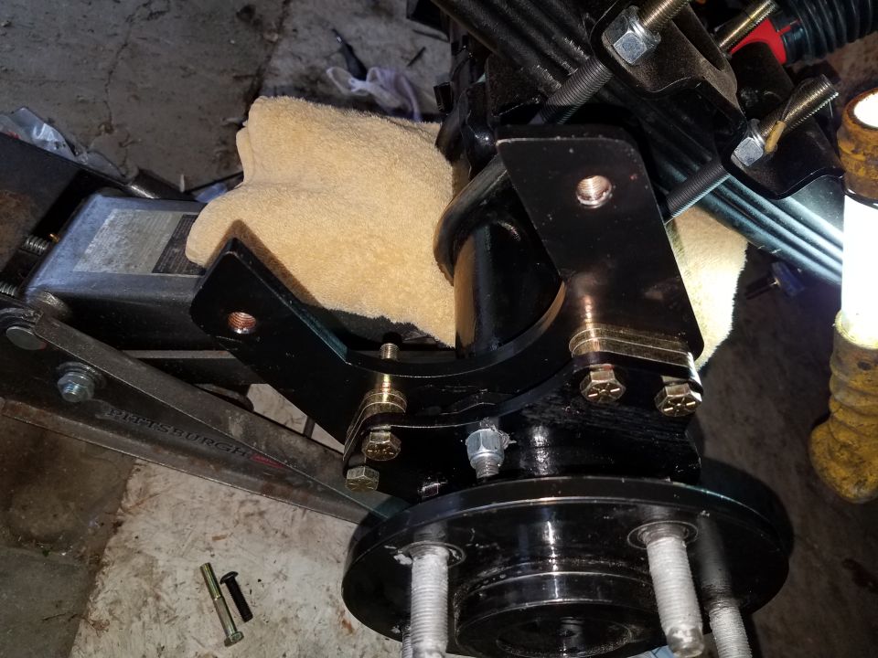 Close-up of vehicle suspension bracket and hub assembly on a floor jack.