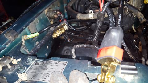 1996 Ford Bronco - A close-up view of the engine bay of a 1996 Ford Bronco, showing various electrical connections and wiring harnesses, including a brass dis…