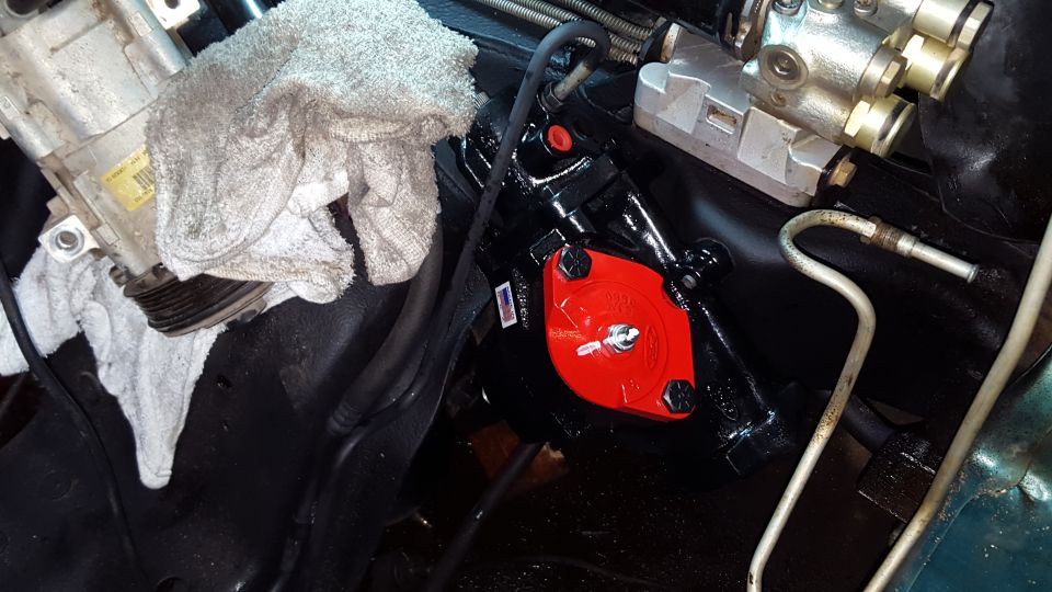 Newly installed black steering gear box with red cap on a vehicle frame.