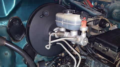 1996 Ford Bronco - The engine bay of a 1996 Ford Bronco shows a close-up of the brake master cylinder and brake booster assembly. The brake fluid reservoir is…