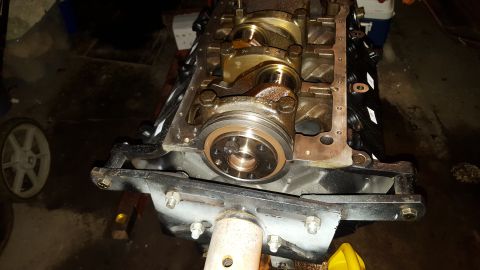 1996 Ford Bronco - A close-up view of the crankshaft and main bearing caps of an engine assembly, likely undergoing repair or rebuild. The engine block is bla…