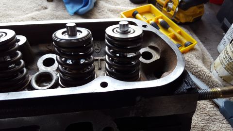 1996 Ford Bronco - A close-up view of a disassembled engine cylinder head with two valve springs and retainers visible. Tools and a can of spray are scattered…