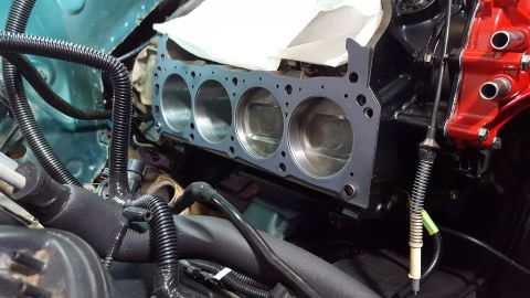 1996 Ford Bronco - A close-up view of a V8 engine block with a new head gasket installed over the cylinders. The engine bay shows various hoses and wiring, wi…