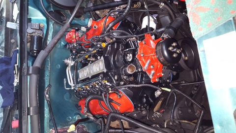 1996 Ford Bronco - A close-up, high-angle view of a black engine with red accents, likely a Ford Bronco, is installed in a vehicle's engine bay. Various hoses…