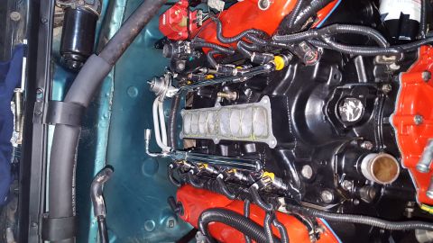 1996 Ford Bronco - A close-up view of a black engine with red accents and fuel injectors, showing intricate wiring and plumbing. The engine bay appears to be…