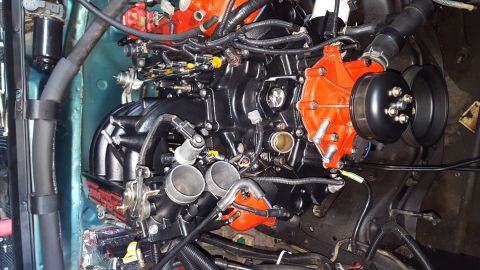 1996 Ford Bronco - A close-up view of a black engine with orange accents, likely a Ford Bronco, is installed in an engine bay. The engine features a dual thro…