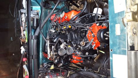 1996 Ford Bronco - A close-up, top-down view of a black and orange engine with various hoses and wiring harnesses, installed in a vehicle's engine bay.