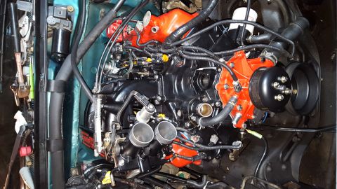 1996 Ford Bronco - A close-up, top-down view of a rebuilt engine, likely for a 1996 Ford Bronco, featuring a black intake manifold and bright orange valve cov…
