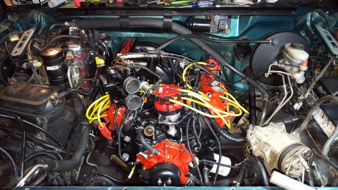 1996 Ford Bronco - The engine bay of a teal 1996 Ford Bronco is shown, featuring a rebuilt engine with red accents on the distributor cap, spark plug wire hol…