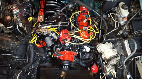1996 Ford Bronco - A top-down view of a modified V8 engine bay, featuring bright red components like the distributor cap and ignition coils, contrasting with…