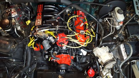 1996 Ford Bronco - A detailed, high-angle view of a modified Ford 5.8L V8 engine bay, featuring bright red performance parts like the distributor cap and inta…