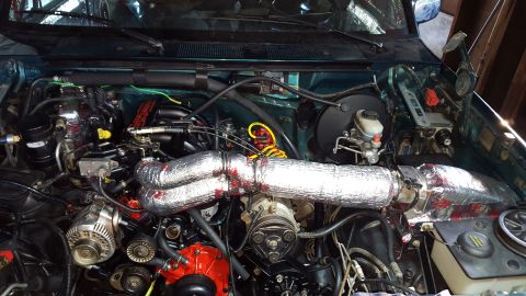 1996 Ford Bronco - The engine bay of a 1996 Ford Bronco is shown, featuring a complex arrangement of hoses, wires, and engine components, many of which are co…