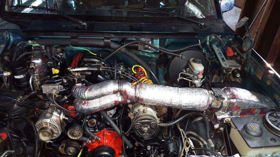 Engine bay of a 1996 Ford Bronco with insulated hoses and various engine parts.