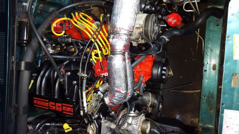 1996 Ford Bronco - The engine bay of a 1996 Ford Bronco shows a modified 5.8L EFI engine with red accents on the distributor cap and engine block, and yellow…