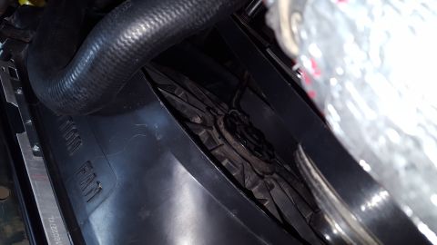 1996 Ford Bronco - A close-up view of a vehicle's engine bay shows a black radiator fan shroud with embossed text that reads "RADIATOR FAN". A black hose is v…