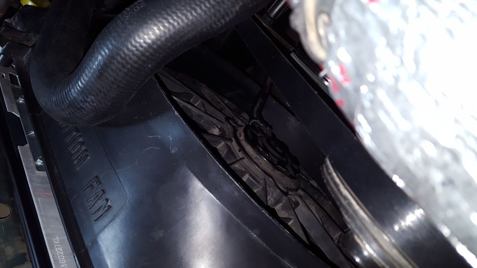 Close-up of a black radiator fan shroud with text "RADIATOR FAN" and a black hose.