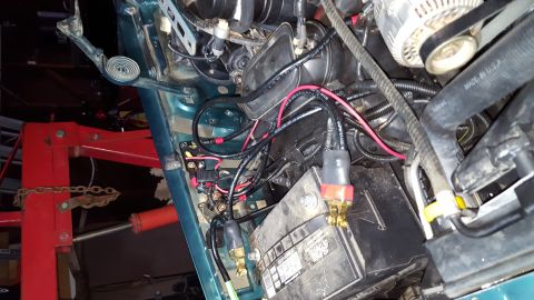 1996 Ford Bronco - A close-up view of the engine bay of a 1996 Ford Bronco, focusing on the battery and wiring modifications. The battery terminals have after…