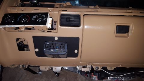 1996 Ford Bronco - The interior dashboard of a vehicle shows a modified center console with an installed power inverter and USB ports. The climate control pan…