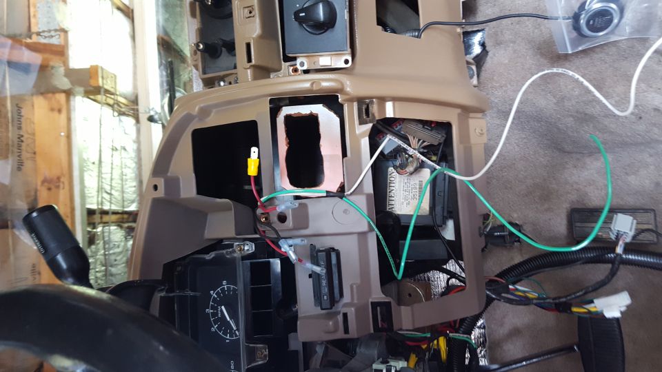 Vehicle dashboard with exposed wiring and a push-to-start button.