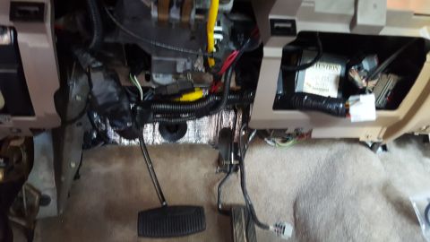 1996 Ford Bronco - The interior of a vehicle's dashboard area is shown with various wires, pedals, and electronic components exposed. Sound deadening material…