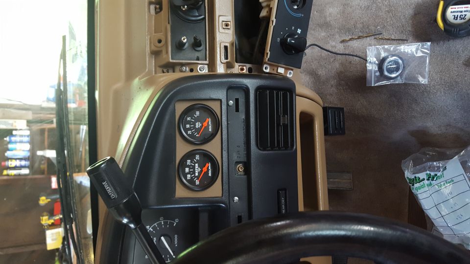 Vehicle dashboard interior with gauges, air vent, gear shifter, and steering wheel.