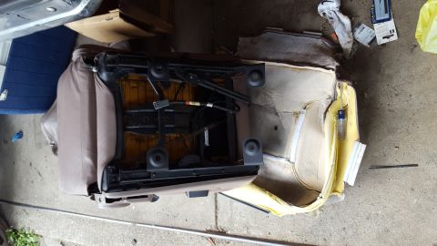 1996 Ford Bronco - A disassembled car seat, likely from a 1996 Ford Bronco, is shown with its internal mechanisms and padding exposed. A screwdriver is insert…