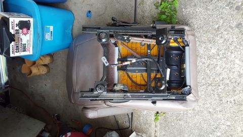 1996 Ford Bronco - A disassembled car seat with exposed yellow foam padding and black metal frame is shown from a top-down perspective. The seat is resting on…