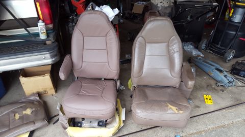 1996 Ford Bronco - Two car seats, one in good condition and one showing significant wear and tear, are displayed outdoors next to a vehicle. The seat on the r…