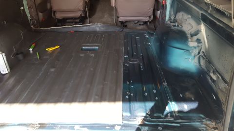 1996 Ford Bronco - The interior floor of a vehicle is shown, with one side covered in dark material and the other side showing the bare metal floor with some…
