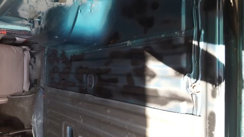 1996 Ford Bronco - The interior of a vehicle shows a section of the floor pan that has been treated with a dark protective coating. A portion of a tan seat is…
