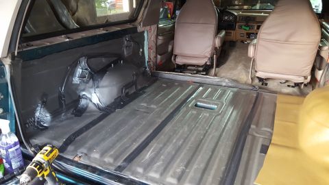 1996 Ford Bronco - The interior of a 1996 Ford Bronco is shown with the rear cargo area and front seats visible. The rear floor is covered in dark material, a…
