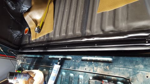 1996 Ford Bronco - The interior of a vehicle's bed area shows sound deadening material being applied to the walls and a black rubber seal being installed alon…