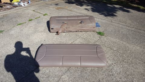 1996 Ford Bronco - Two car seats are laid out on a concrete surface. The seat in the foreground is a bench seat, while the seat in the background appears to b…