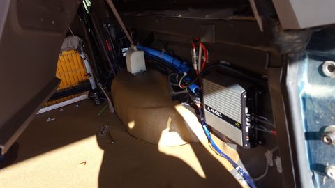 1996 Ford Bronco - The interior of a vehicle shows a JL Audio amplifier mounted to the side panel, with various wires and blue tubing running nearby. The carp…