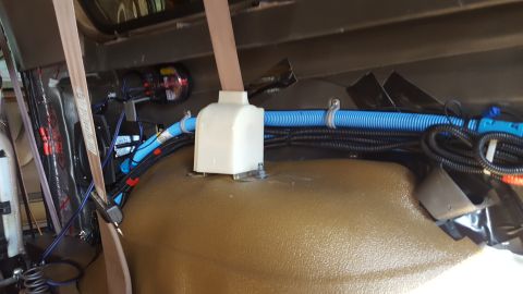 1996 Ford Bronco - The interior of a vehicle shows a complex wiring setup with blue and black conduits running along the floor and up the side panel. A white…