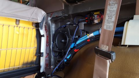 1996 Ford Bronco - The interior of a vehicle shows a car speaker and amplifier installed behind a partially disassembled seat. Blue and black wiring is neatly…
